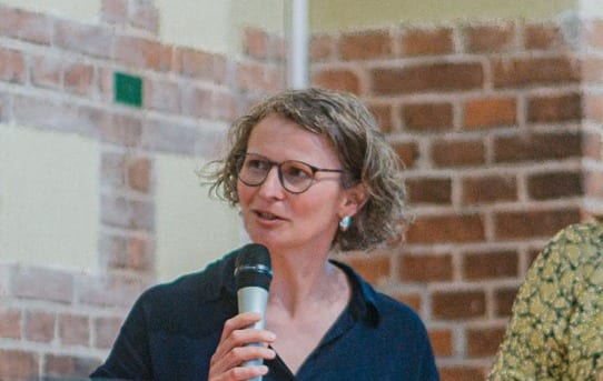 Eva spricht bei einer Podiumsdiskussion ins Mikrofon